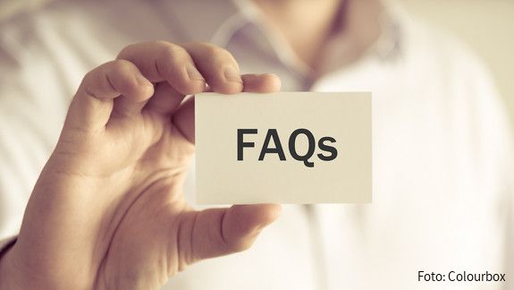 Closeup on businessman holding a card with text FAQs , business concept image with soft focus background and vintage tone